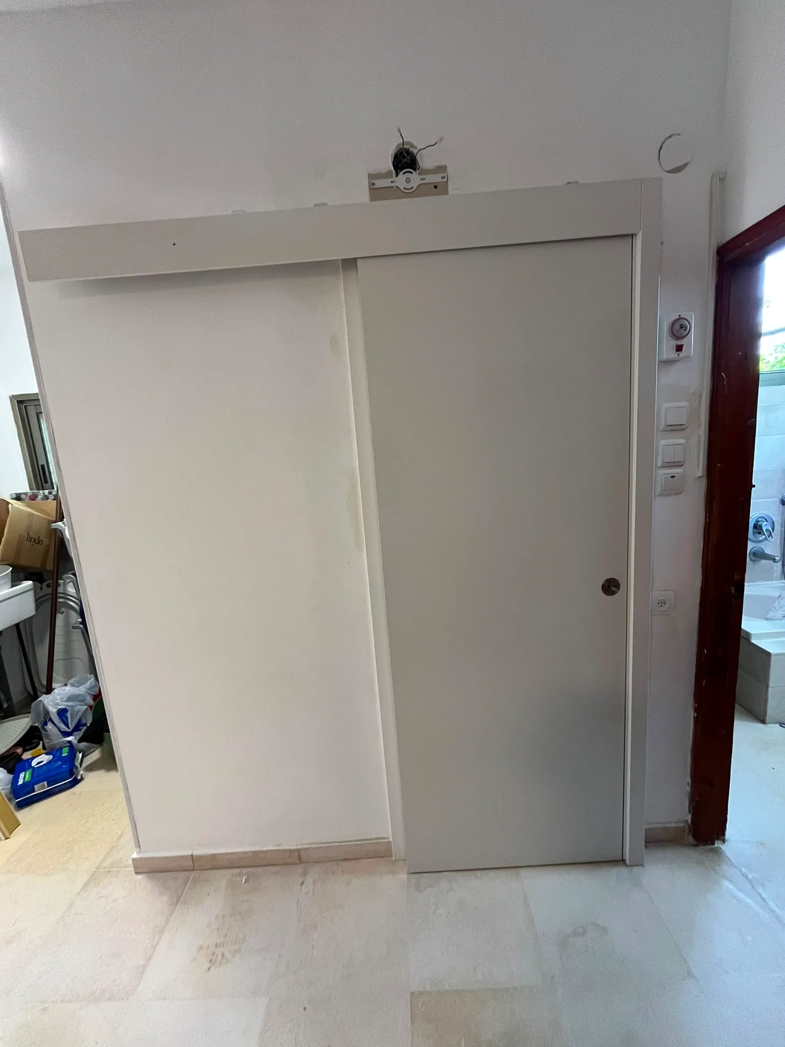דלת הזזה לבנה על מסילה עליונה בכניסה לחדר רחצה